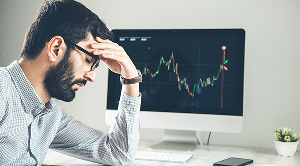 Man at computer stressed about stock going up or down.